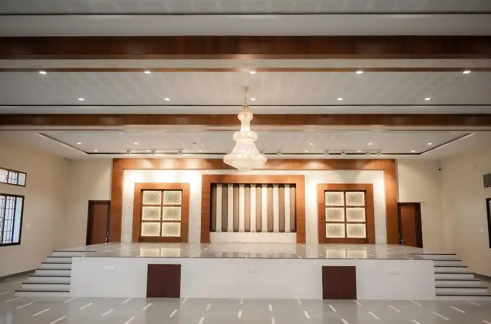 A spacious room featuring an elegant chandelier and a prominent stage, ideal for events and performances.