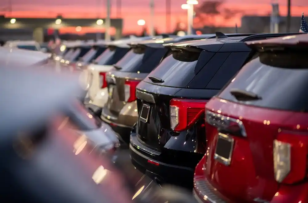 A row of parked cars neatly arranged in a parking lot under clear blue skies.