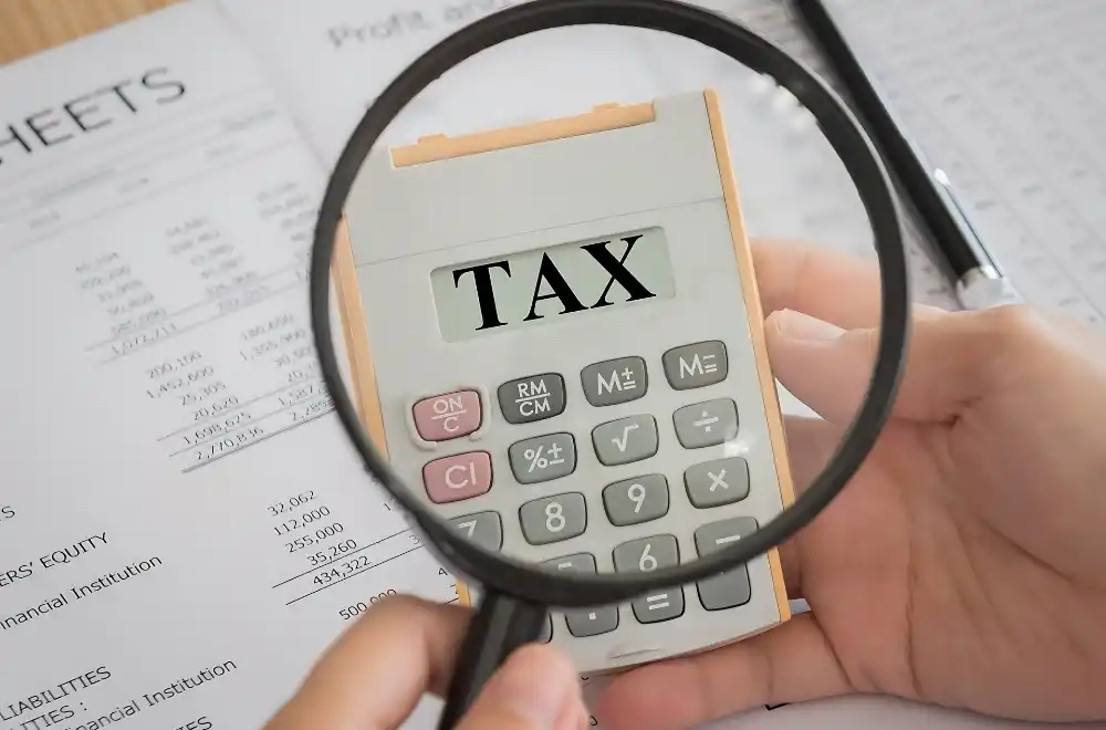 A tax calculator displayed alongside a magnifying glass, symbolizing detailed financial analysis and scrutiny of tax calculations.